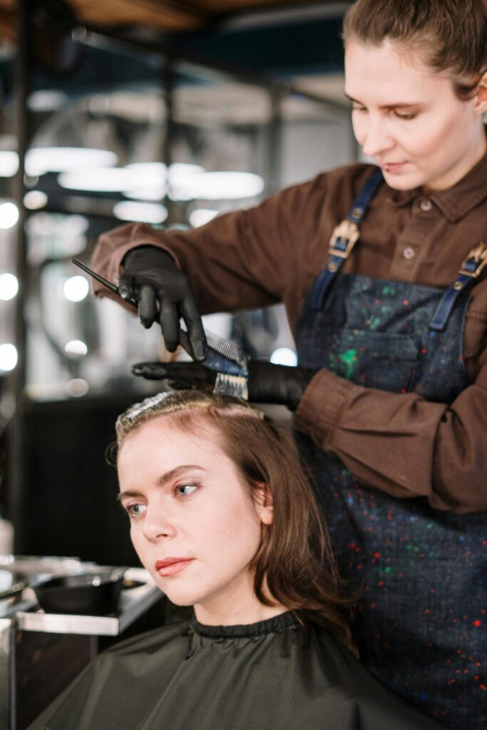 A hairstylist expertly dyes a woman's hair in a contemporary salon setting, highlighting beauty and care.